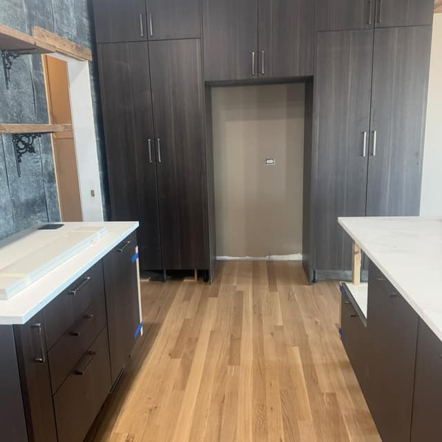 Finished light hardwood floor in a kitchen with dark cabinetry