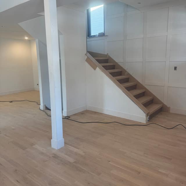 Freshly sanded hardwood floor and staircase in a finished basement