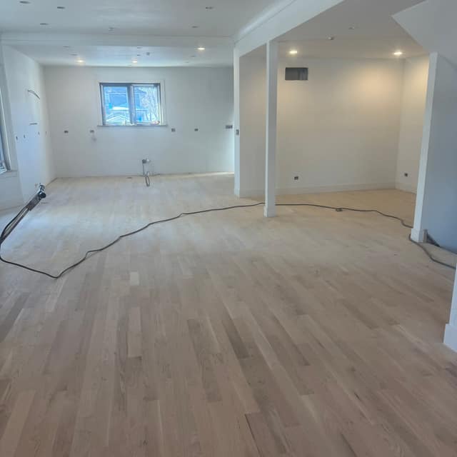 Large open room with a freshly sanded, unfinished hardwood floor