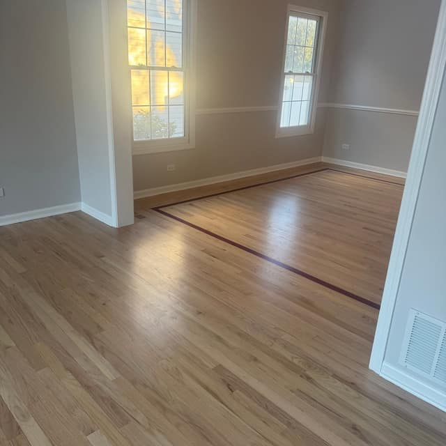 Refinished natural wood floor with a dark decorative border inlay
